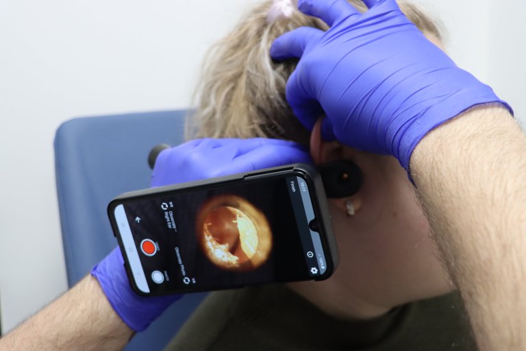 An audiologist using a video otoscope to take some pictures of a patient's ear canal.