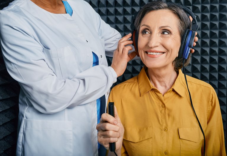 An audiologist putting headphones on a patient for a hearing assessment.