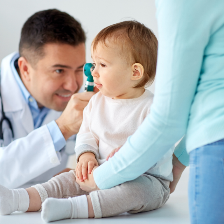A doctor carefully examining a baby's ear.