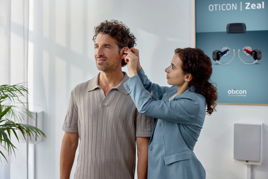 An audiologist fitting a patient with the new Oticon Zeal hearing aids.