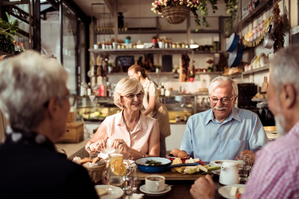 Close up of a group of seniors enjoying food in a restaurant.