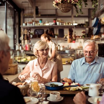 Close up of a group of seniors enjoying food in a restaurant.