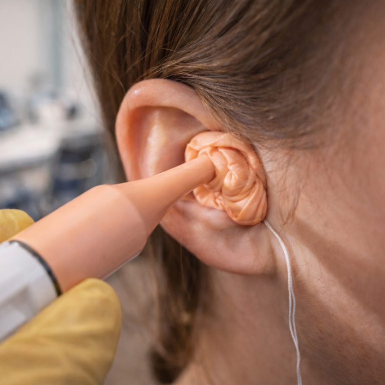 An audiologist takes an ear impression from a patient.