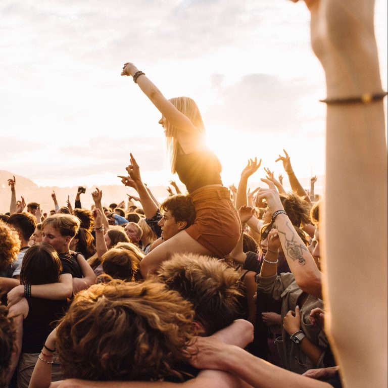Energetic crowd enjoying live music at a festival during sunset