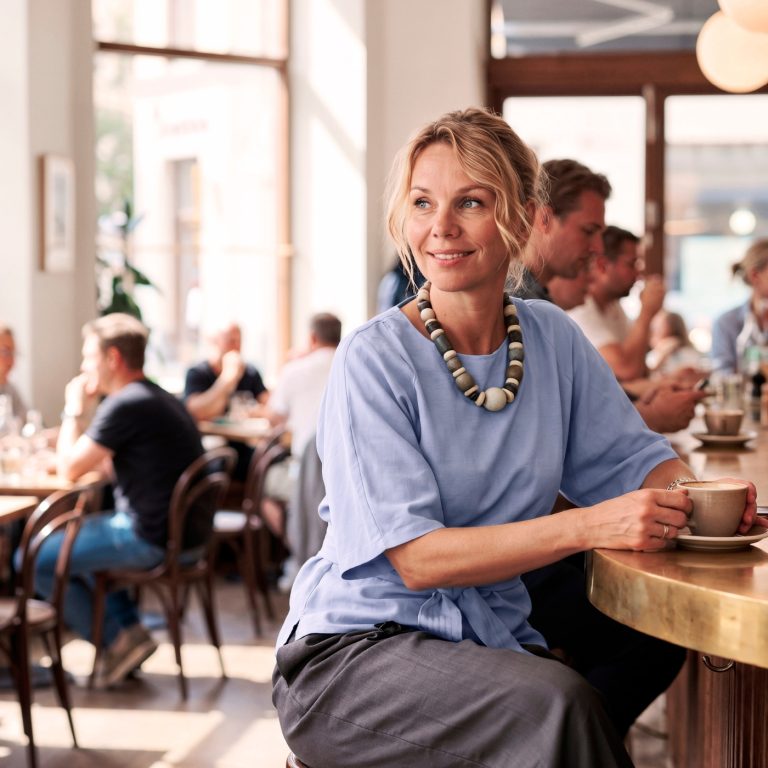 Woman smiling in a busy coffee place.