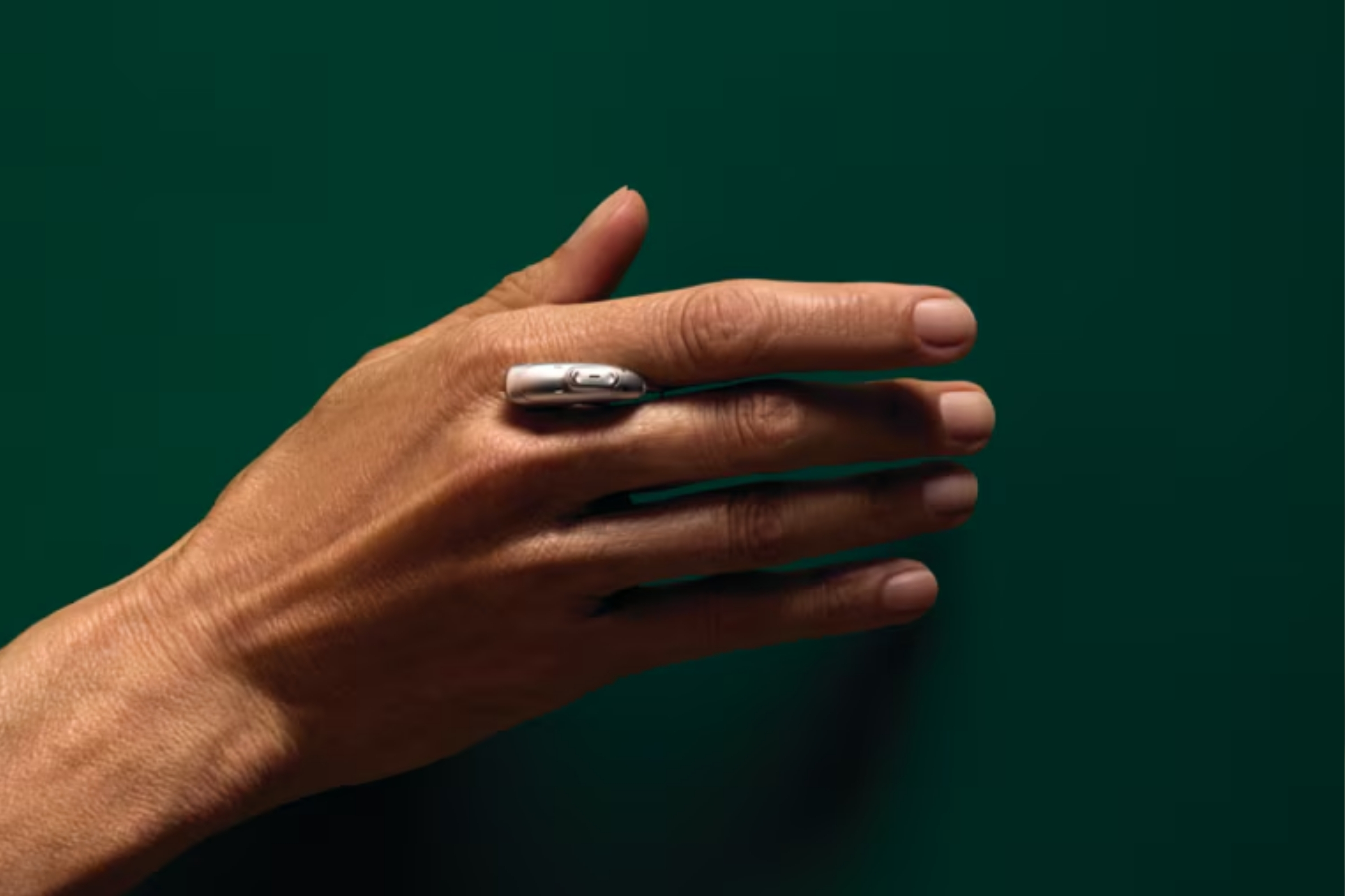 A hand with a hearing aid between fingers.